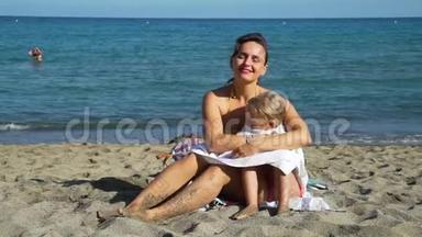妈妈在海滩上用毛巾给女儿盖被子